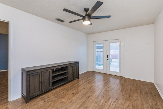 empty room with ceiling fan, visible vents, light wood-style flooring, baseboards, and french doors