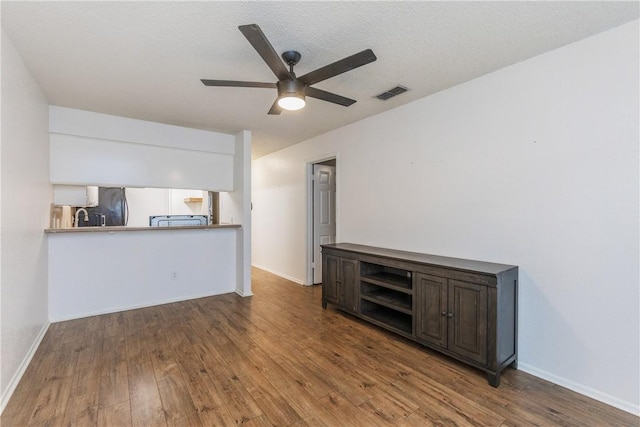 unfurnished living room with wood finished floors, visible vents, ceiling fan, and baseboards