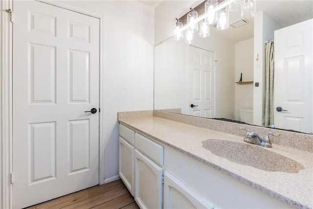bathroom featuring toilet, vanity, and wood finished floors