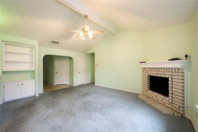 unfurnished living room featuring built in features, ceiling fan, carpet flooring, lofted ceiling with beams, and a brick fireplace