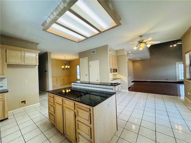 kitchen featuring light tile patterned floors, a kitchen island, black electric cooktop, decorative light fixtures, and dark stone counters