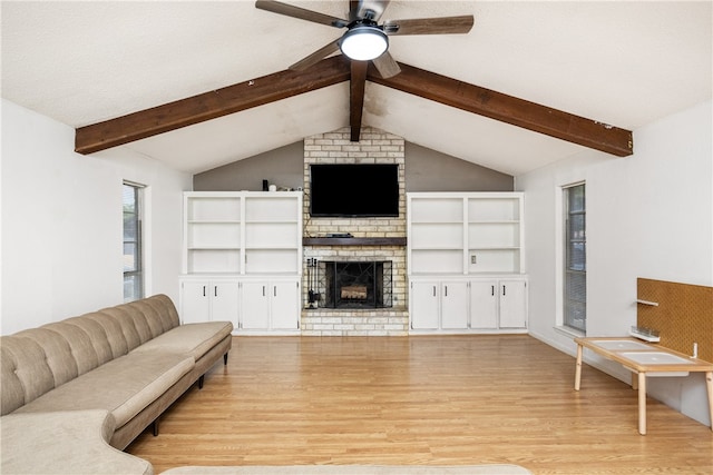 living room featuring a brick fireplace, lofted ceiling with beams, light hardwood / wood-style floors, and ceiling fan