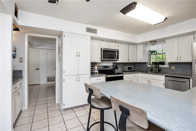 kitchen with stainless steel appliances, white cabinets, and a textured ceiling