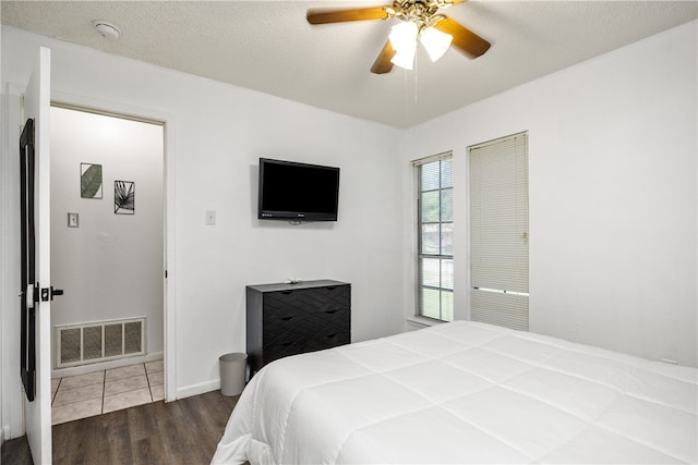 bedroom featuring ceiling fan, a textured ceiling, and dark hardwood / wood-style flooring