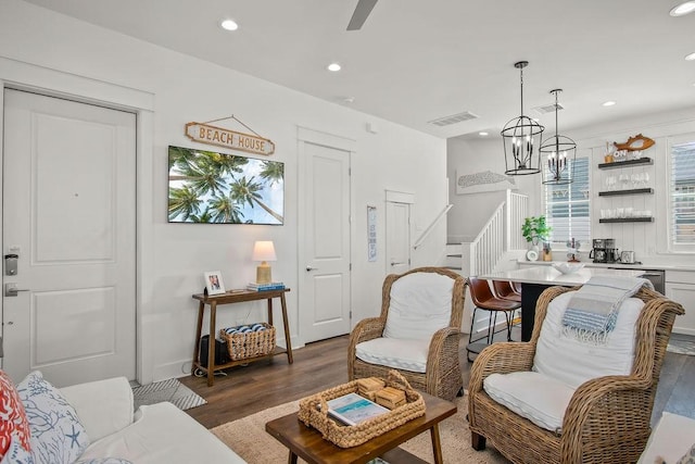 living room with visible vents, stairway, recessed lighting, an inviting chandelier, and wood finished floors