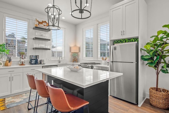 kitchen featuring appliances with stainless steel finishes, a kitchen island, light wood-type flooring, and light countertops