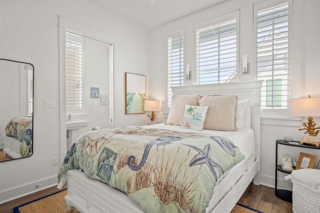 bedroom featuring ensuite bathroom, baseboards, and wood finished floors