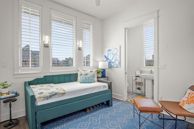 bedroom with wood finished floors, ensuite bathroom, baseboards, and a sink