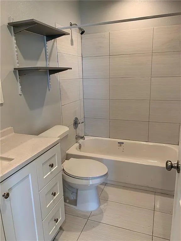 full bathroom with toilet, tiled shower / bath combo, vanity, and tile patterned floors