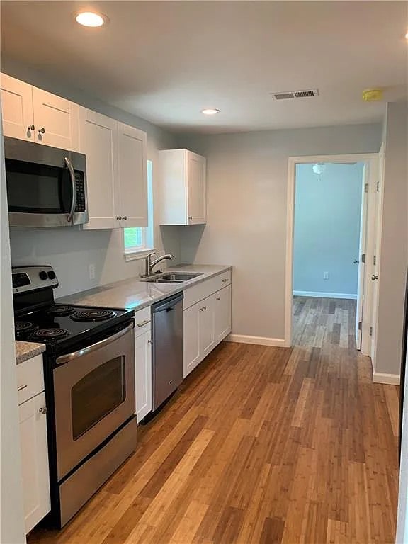 kitchen featuring white cabinetry, appliances with stainless steel finishes, sink, and light hardwood / wood-style floors