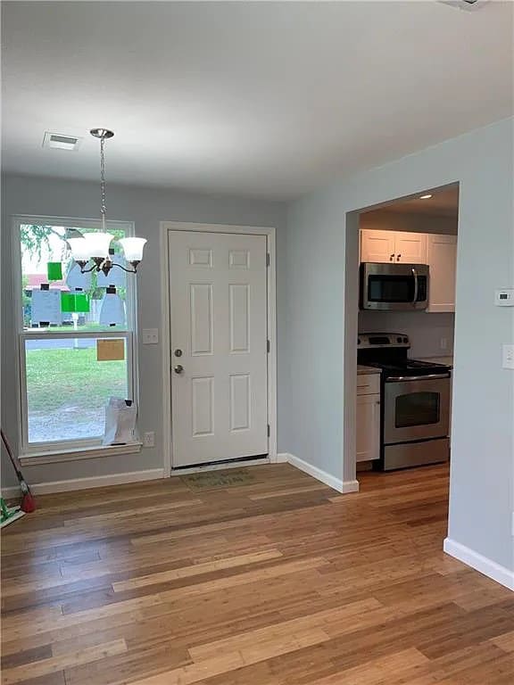 interior space featuring light wood-type flooring and a notable chandelier