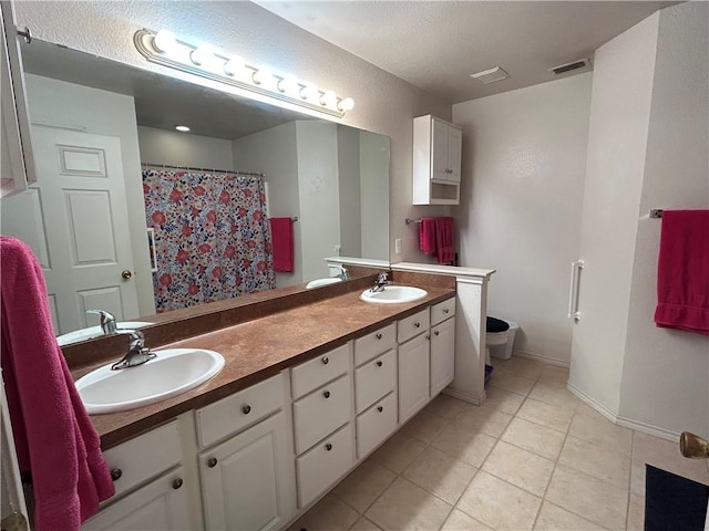 bathroom with toilet, double vanity, a sink, and visible vents