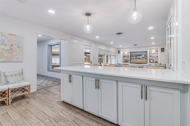 kitchen with pendant lighting, light hardwood / wood-style flooring, and built in features