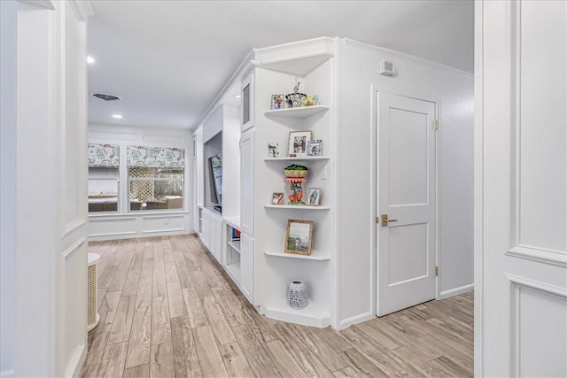 hall with light hardwood / wood-style floors and crown molding