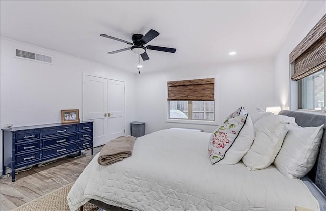 bedroom with multiple windows, ceiling fan, a closet, and hardwood / wood-style floors