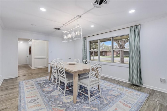 dining area featuring wood-type flooring, crown molding, and a chandelier