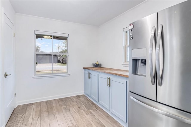 kitchen with stainless steel fridge, wooden counters, and light wood-type flooring