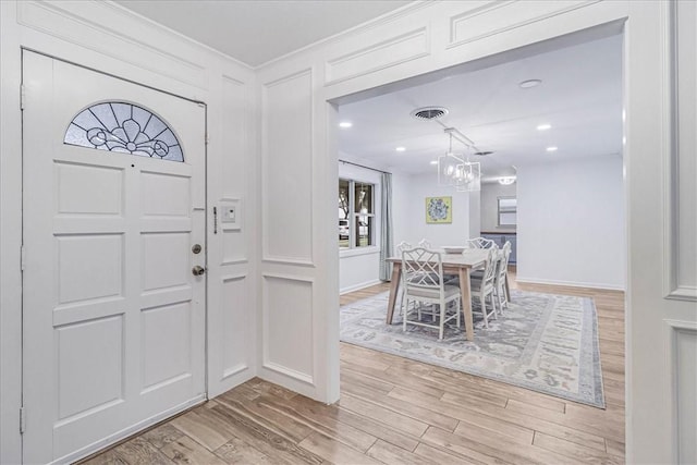 foyer featuring light wood-type flooring and an inviting chandelier