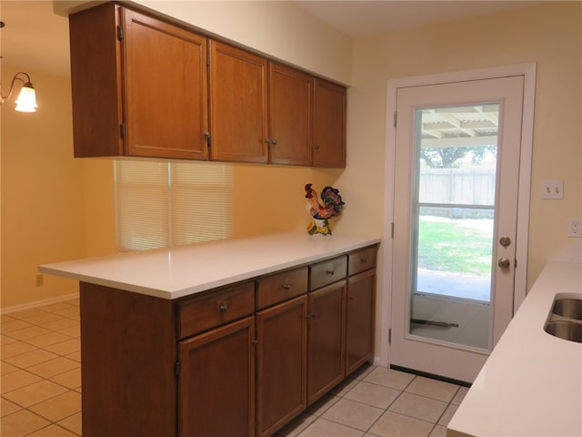 726 John Lee St, Corpus Christi, TX 78412 - kitchen with light countertops, light tile patterned flooring, a peninsula, brown cabinetry, and a sink