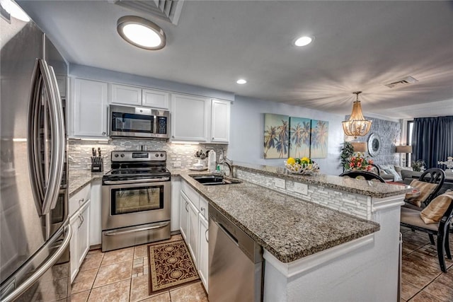 kitchen featuring sink, appliances with stainless steel finishes, white cabinets, decorative light fixtures, and kitchen peninsula