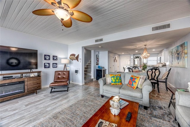 living room featuring ceiling fan with notable chandelier and light hardwood / wood-style flooring