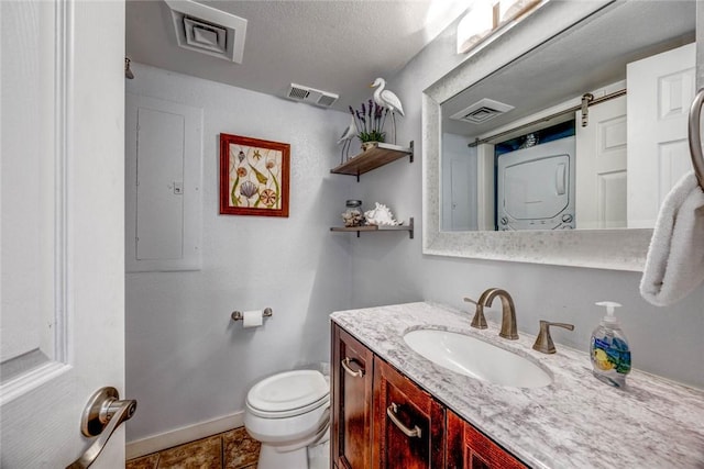 bathroom featuring stacked washer and dryer, tile patterned flooring, electric panel, vanity, and toilet