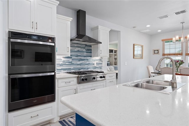 108 Bayshore Drive, Ingleside On The Bay, TX 78362 - kitchen featuring multiple ovens, wall chimney range hood, stainless steel gas cooktop, a sink, and decorative backsplash