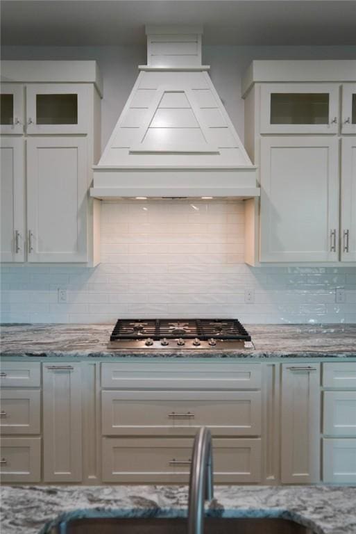 3525 Sahar Lk, Corpus Christi, TX 78380 - kitchen featuring stainless steel gas cooktop, custom exhaust hood, tasteful backsplash, and glass insert cabinets