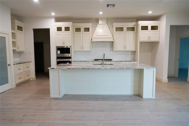 3525 Sahar Lk, Corpus Christi, TX 78380 - kitchen featuring visible vents, white cabinetry, a center island with sink, custom range hood, and stainless steel appliances
