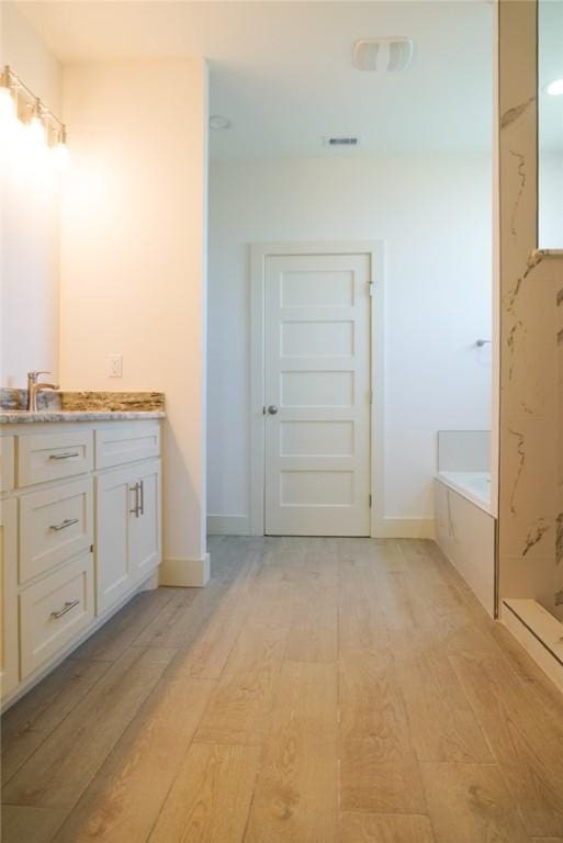 3525 Sahar Lk, Corpus Christi, TX 78380 - bathroom with vanity, baseboards, a walk in shower, a garden tub, and wood finished floors
