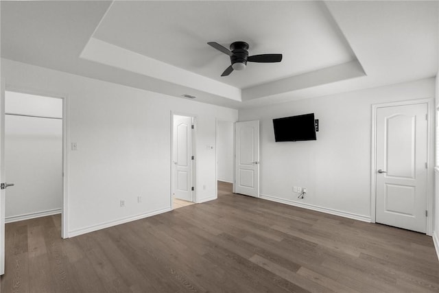 13901 Mingo Cay Ct Unit F, Corpus Christi, TX 78418 - unfurnished bedroom featuring a tray ceiling, wood finished floors, a walk in closet, baseboards, and ceiling fan