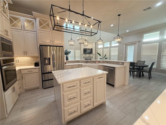 8137 Berenstain Dr, Corpus Christi, TX 78414 - kitchen featuring stainless steel appliances, a peninsula, a kitchen island, tasteful backsplash, and a sink