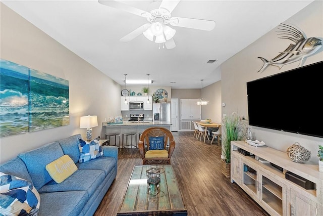 living room with visible vents, dark wood finished floors, and ceiling fan with notable chandelier