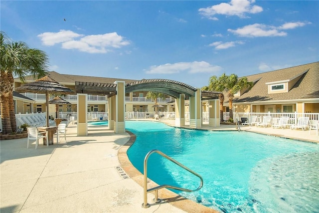 community pool with a patio area, fence, and a pergola