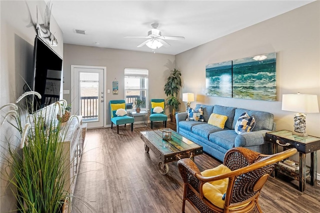 living room with ceiling fan, visible vents, and wood finished floors