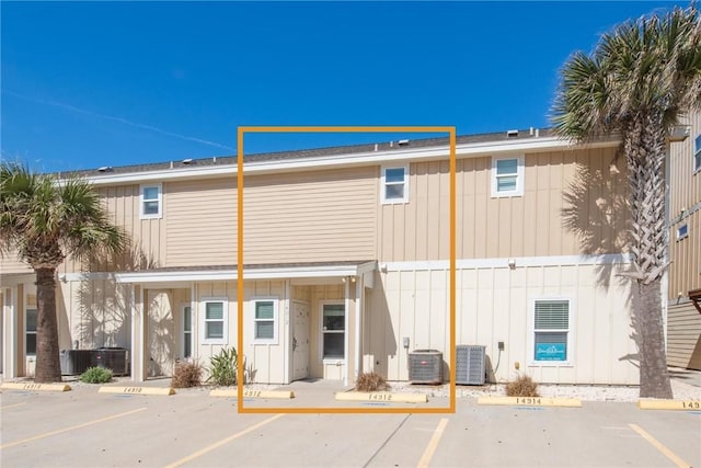 view of building exterior featuring uncovered parking and cooling unit