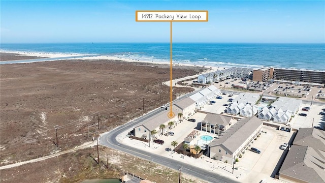 birds eye view of property with a water view and a beach view