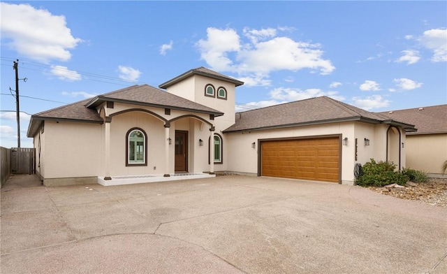 mediterranean / spanish-style home with stucco siding, driveway, an attached garage, and fence