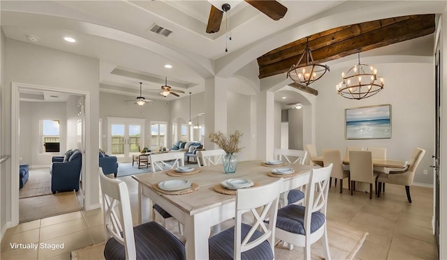 dining area with arched walkways, light tile patterned flooring, ceiling fan with notable chandelier, visible vents, and a tray ceiling