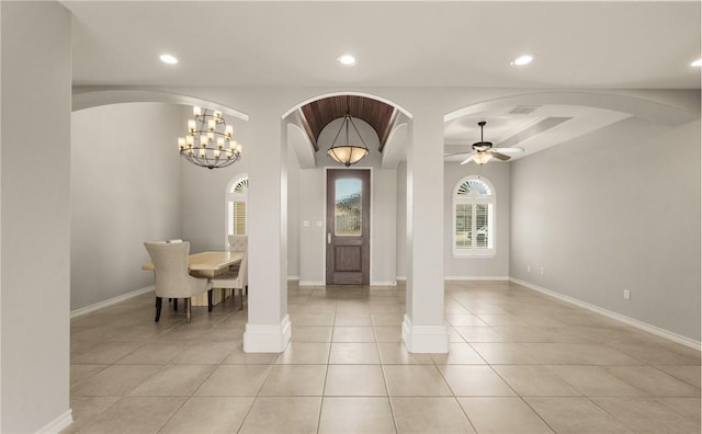 foyer featuring ceiling fan with notable chandelier, decorative columns, and light tile patterned flooring