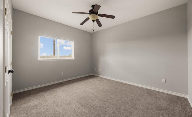 carpeted spare room with a ceiling fan and baseboards