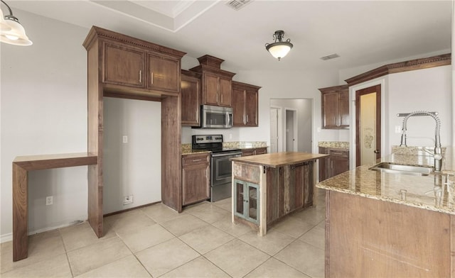 kitchen featuring light tile patterned floors, stainless steel appliances, visible vents, a sink, and light stone countertops