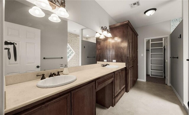 full bath with a walk in closet, visible vents, a sink, and double vanity