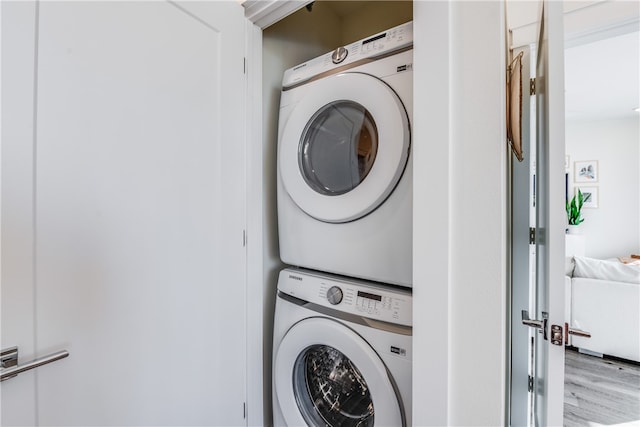 laundry area with stacked washing maching and dryer and light hardwood / wood-style floors