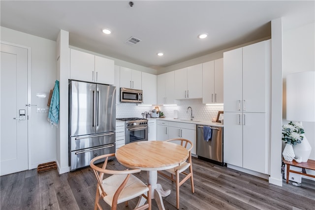 kitchen featuring white cabinetry, sink, dark hardwood / wood-style floors, high end appliances, and backsplash