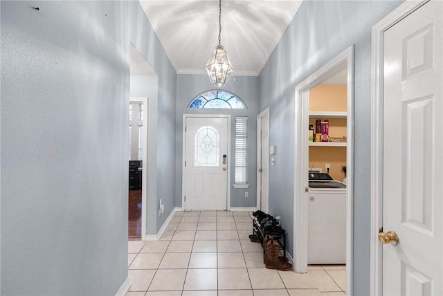 tiled entrance foyer featuring an inviting chandelier, washer / clothes dryer, and crown molding