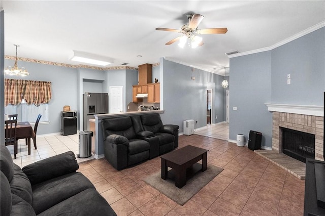 tiled living room featuring ceiling fan with notable chandelier, a fireplace, and ornamental molding