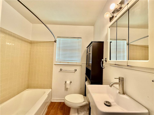 full bathroom with hardwood / wood-style floors, toilet, sink, and tiled shower / bath