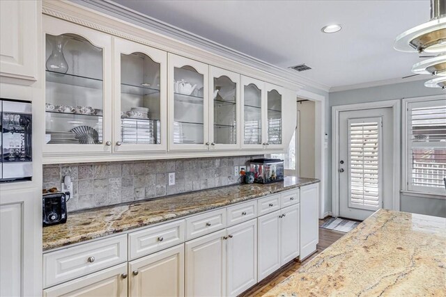 209 Jackson Pl, Corpus Christi, TX 78411 - kitchen featuring backsplash, glass insert cabinets, light stone countertops, crown molding, and wood finished floors
