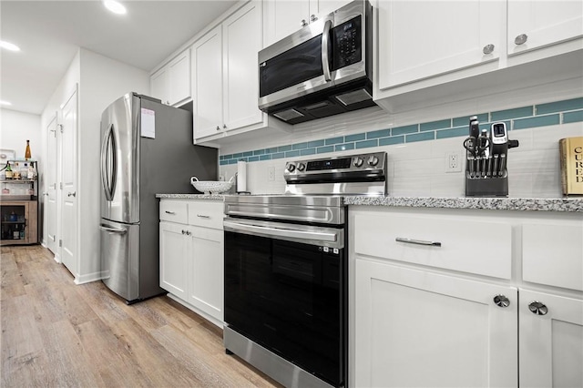 607 Huisache Lane, Ingleside On The Bay, TX 78362 - kitchen featuring appliances with stainless steel finishes, backsplash, white cabinets, light wood-style floors, and recessed lighting